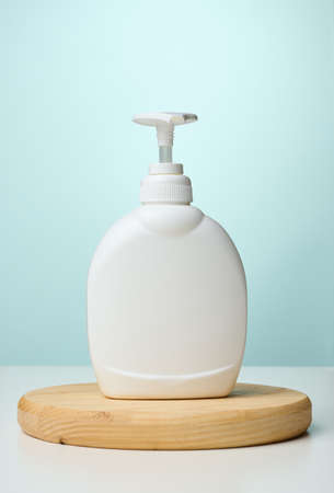White plastic container with a pump for cosmetic liquid, liquid soap on the tableの写真素材