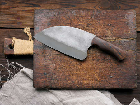 Large kitchen knife on an empty wooden cutting board, top view