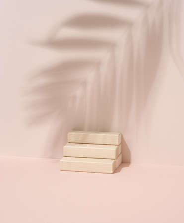 Wooden steps and shadow from a palm leaf on a beige background. Stage for demonstration and advertising of products, cosmetics, goodsの写真素材