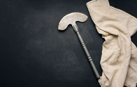 Big kitchen knife on black table with cotton napkin, top view. copy space