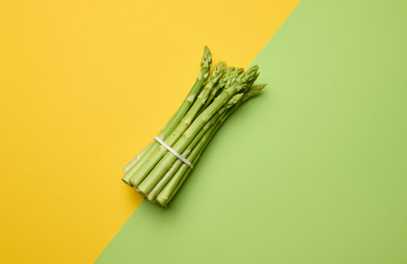 Bunch of fresh asparagus on green paper background, top viewの写真素材