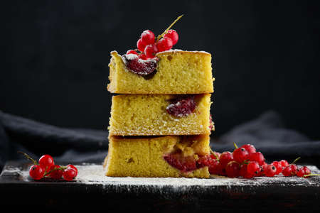 A stack of square slices of baked plum biscuit cake, sprinkled with powdered sugar on topの写真素材