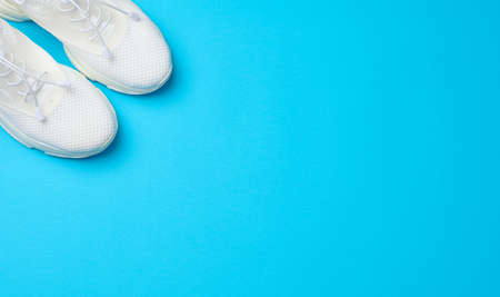 White textile sneakers on a blue background, top viewの写真素材
