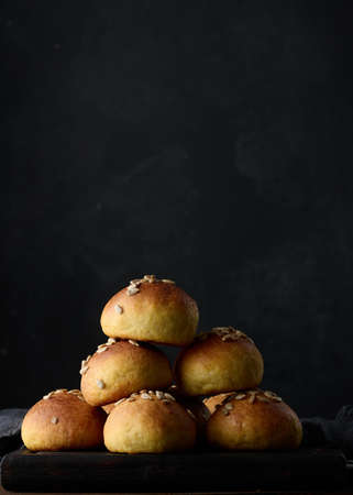 Baked round buns on a wooden table, black backgroundの写真素材