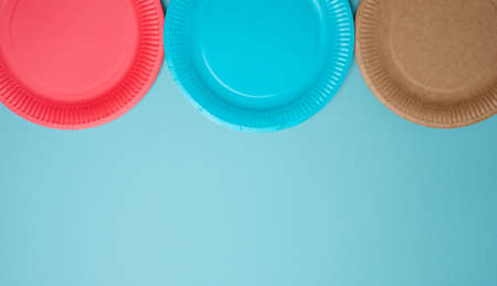 Empty paper disposable plates on a blue background, top view. The concept of rejection of plastic, environmental conservationの写真素材