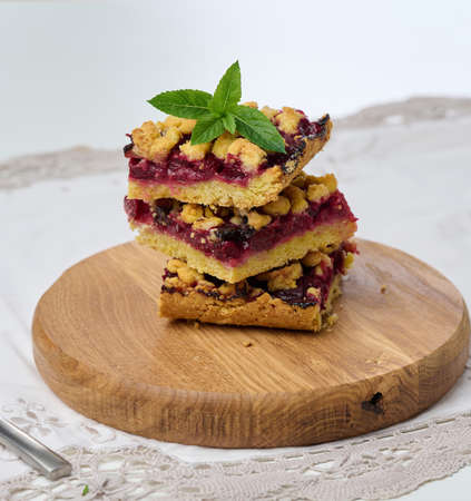 Square slices of cherry crumble lie in a stack on a white background