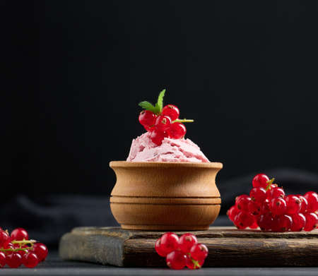 Pink scoops of popsicles with red currants on a black table. ice cream