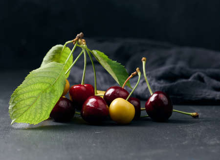 Ripe red and yellow cherries on a black background. summer berryの写真素材