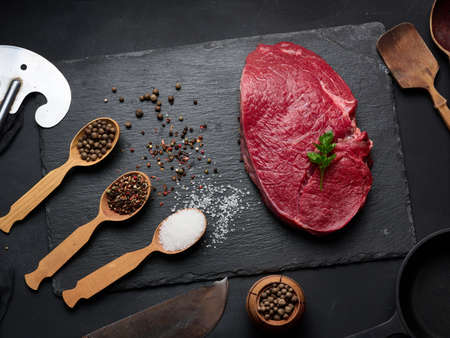 Raw beef tenderloin lies on a board, black table. View from aboveの写真素材