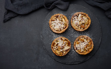 Fruit mini tart with apples on a black round graphite board, top viewの写真素材