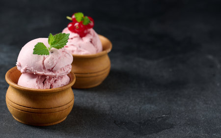 Pink scoops of popsicles with red currants on a black table. ice creamの写真素材
