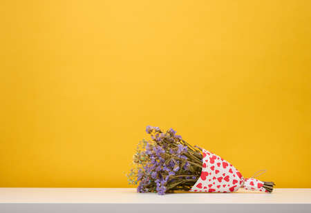 Dry bouquet of wild flowers on a yellow background, copy spaceの写真素材