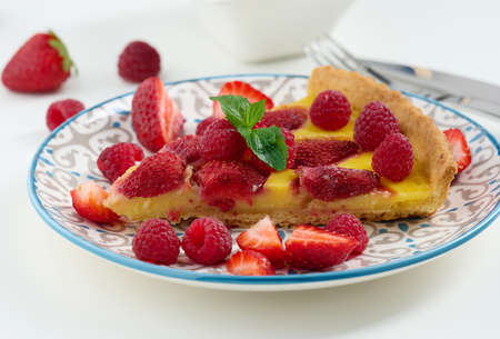 Round quiche with red strawberries and raspberries on a white table, top viewの写真素材