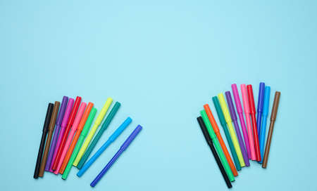 Stack of multicolored felt-tip pens on a blue background, flat lay