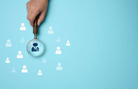 Search and selection of personnel in the company. Effective personnel management, leader identification. Magnifying glass and staff icons on blue backgroundの写真素材