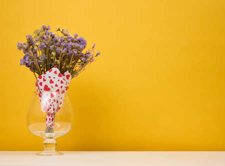 Dry bouquet of wild flowers in a vase on a yellow background, copy spaceの写真素材