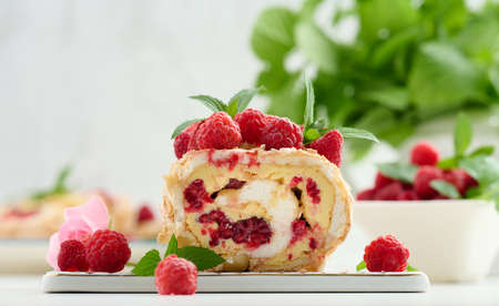 Baked meringue roll with cream and fresh red raspberry on a white board, delicious dessertの写真素材