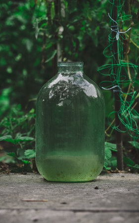 A glass transparent ten liter bottle of water stands in the gardenの写真素材