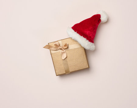 Square box and red santa hat on a beige background. Christmas decor, top viewの写真素材