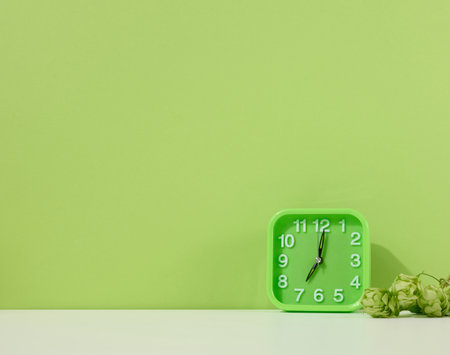 Green alarm clock stands on a white table, green background. back to school. copy spaceの写真素材
