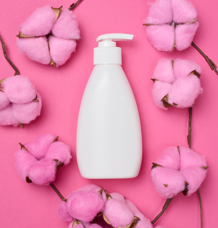 White plastic bottle with pump on a pink background. Containers for cosmetics, top viewの写真素材