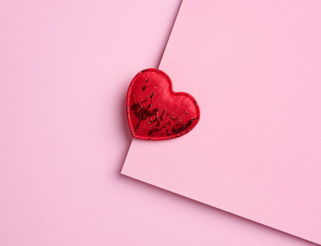Red textile heart on a pink paper background, top view.の写真素材