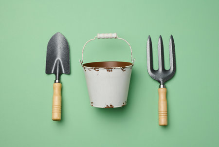 Miniature garden tools in a metal bucket on a green background, top viewの写真素材