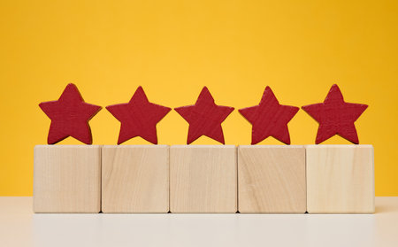 Five stars on wooden cubes, yellow background. Service evaluation concept, high rating