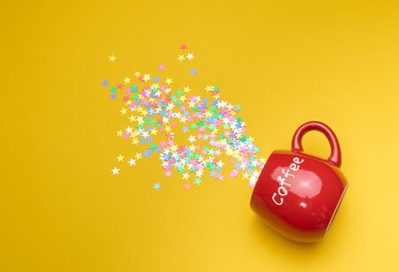 Shiny multicolored star confetti scattered on a yellow background, festive backdrop for birthday, valentines day. Festive decoration elementsの写真素材
