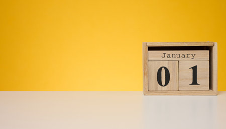 Wooden calendar made of cubes on a yellow background. Date January 1st, beginning of the yearの写真素材