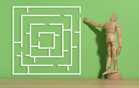 Wooden figurine of a mannequin and a labyrinth on a green background. solution search conceptの写真素材