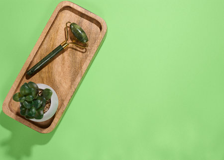 Jade facial massager, an item for cosmetic procedures on a green background, top viewの写真素材