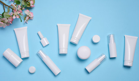 White plastic tubes, jars, and containers for cosmetic products on a blue background, advertising and branding of productsの写真素材
