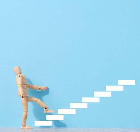A wooden mannequin and drawn steps going up, a concept of achieving a goal, strong personalityの写真素材