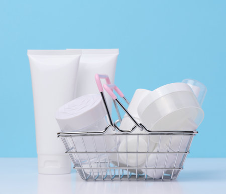 White plastic tubes, jars in a miniature metal basket, containers for cosmetic products. advertising and promotionの写真素材