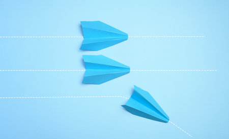 Three paper airplanes are moving forward, one turned sideways, representing the concept of individuality and non-standard thinking.の写真素材