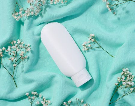 White plastic tube for cosmetics and sprigs of white gypsophila flowers, top viewの写真素材