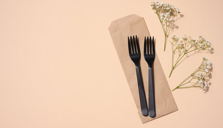 Plastic black forks on a beige background, disposable picnic items, top viewの写真素材