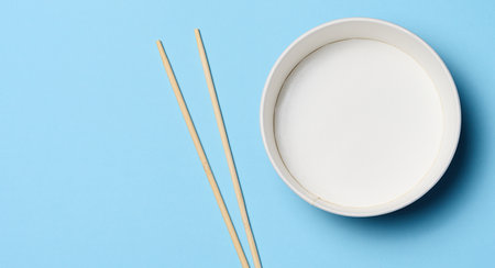 Open empty noodle bowl with and pair of wooden sticks on blue background, top viewの写真素材