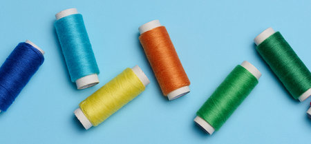 Multicolored spools of sewing threads on a blue background, top viewの写真素材