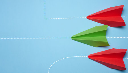 Three paper airplanes are moving forward, one turned sideways, representing the concept of individuality and non-standard thinking.の写真素材