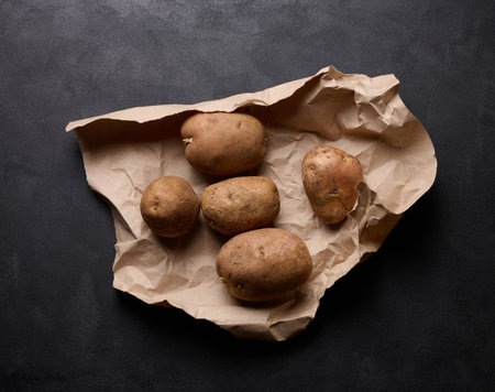 Raw potatoes lie on a brown piece of paper, top viewの写真素材