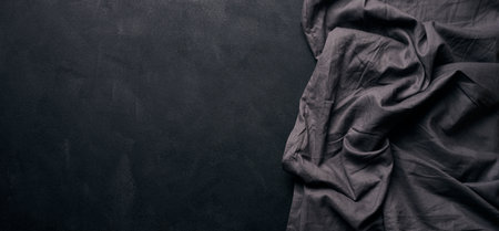 Folded black linen linen kitchen towel on a black background, top view. copy spaceの写真素材
