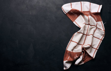Folded linen linen kitchen towel on a black background, top view. copy space