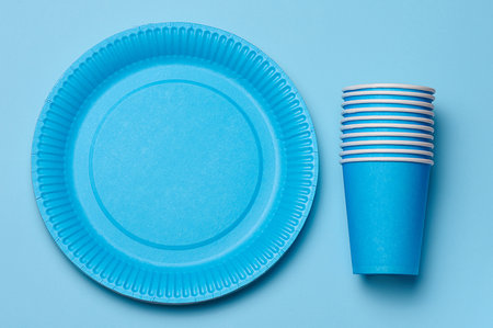 Round disposable blue paper plates and cups for a picnic, recyclable waste, top view.の写真素材