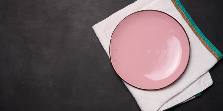 Empty pink ceramic plate on black table, top viewの写真素材