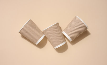 Brown disposable cups for coffee and tea on a beige background, top viewの写真素材