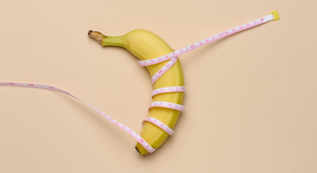 Ripe yellow banana wrapped in a measuring tape, weight loss concept, top viewの写真素材