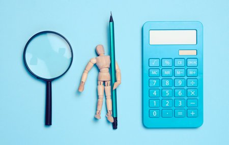 Wooden mannequin, magnifier and blue calculator. Concept of counting budget, taxの写真素材