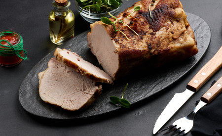 Baked piece of pork balyk on the table with spices. Tenderloin cut into piecesの写真素材